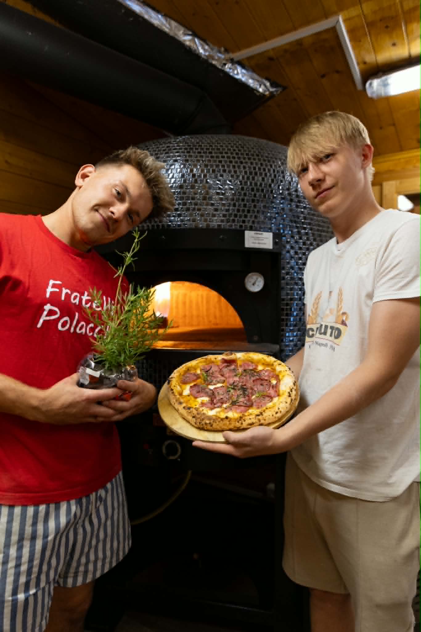 Założyciele pizzerii Fratelli Polacchi w Garwolinie Założyciele Fratelli Polacchi trzymający pizzę neapolitańską przy piecu opalanym drewnem w Garwolinie